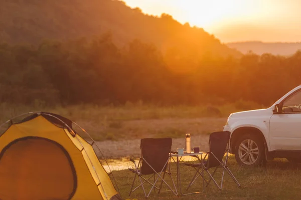 Camping en la playa del río de montaña. coche todoterreno. tienda amarilla. mesa de campamento y sillas — Foto de Stock