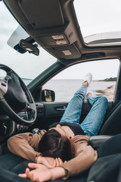 woman resting in car parked at sea beach. summer vacation