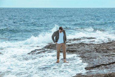 Rüzgarlı yaz tatilinde Rocky Beach 'te yürüyen bir adam. Deniz manzarasının tadını çıkar. yaz zamanı