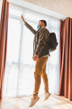 Sırt çantalı, pencerenin yanında duran maskeli adam. Boşluğu kopyala