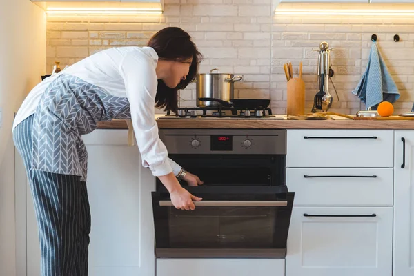 Wanita Cantik Muda Membuka Oven Untuk Memasak Konsep Dapur Rumah — Stok Foto