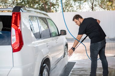 Güçlü bir adam yaz zamanı dışarıda arabasını yıkıyor.