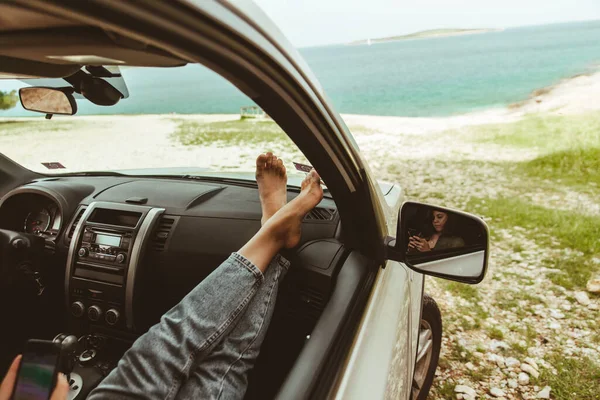 背景に車のダッシュボードの海の女性の足 — ストック写真