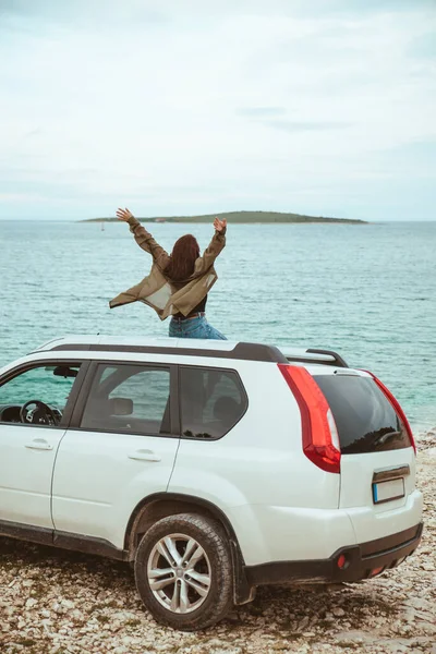 Žena sedící na střeše auta s výhledem na moře — Stock fotografie