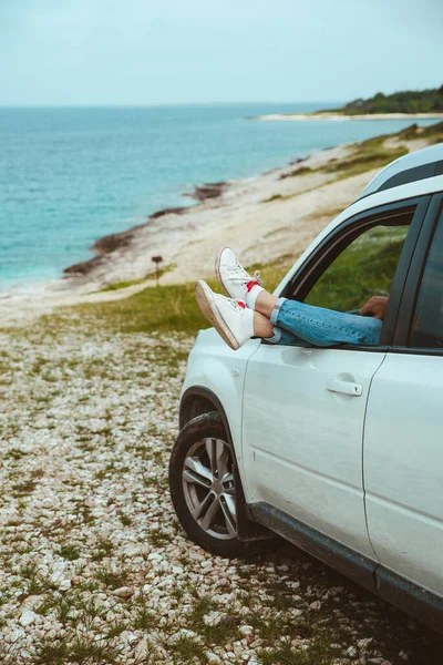 Mannen benen uitsteken uit auto geparkeerd op zee strand — Stockfoto