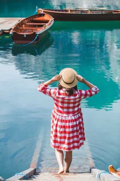 Jovem mulher em sundress vermelho andando pelas escadas para a água do lago — Fotografia de Stock