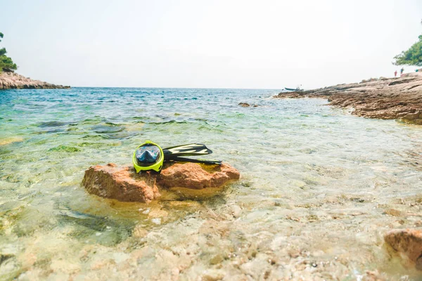 snorkeling mask with flippers at rock in sea water