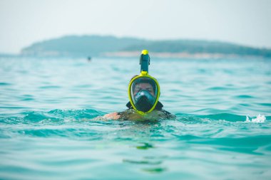Şnorkelli kadın deniz suyunda maske takıyor.