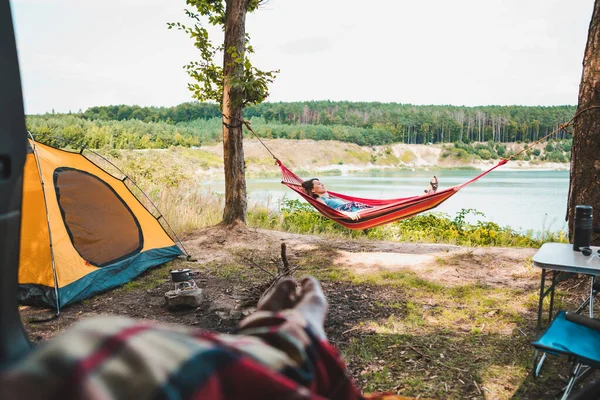 森の湖のハイキングのコンセプトの美しい景色を眺めながらハンモックに寝そべっているキャンプ女のカップルを見る — ストック写真