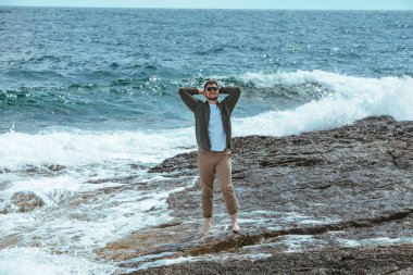 Rüzgarlı yaz tatilinde Rocky Beach 'te yürüyen bir adam. Deniz manzarasının tadını çıkar. yaz zamanı