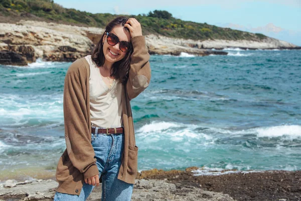 Deniz kıyısında doğanın gücünün tadını çıkaran bir kadın. Rüzgarlı bir hava. Yaz tatili. arkaplandaki dalgalar