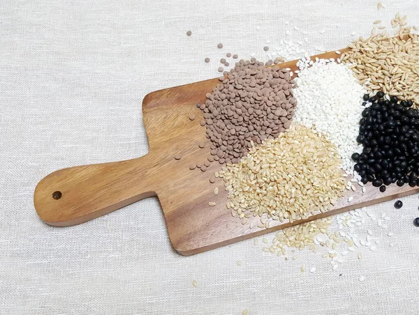 Yulaf, fasulye, glutinous rice, kahverengi pirinç ve mercimek ahşap kesim tahtasının üzerinde.