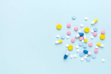 Mavi arka planda renkli ilaç hapları ve haplar. Metin için alanı olan tıbbi şablon.