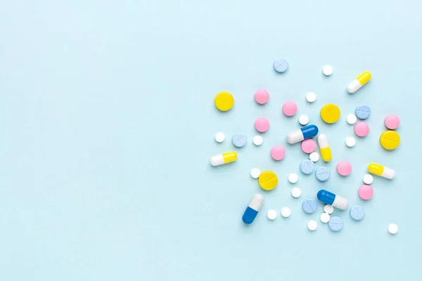 Mavi arka planda renkli ilaç hapları ve haplar. Metin için alanı olan tıbbi şablon.