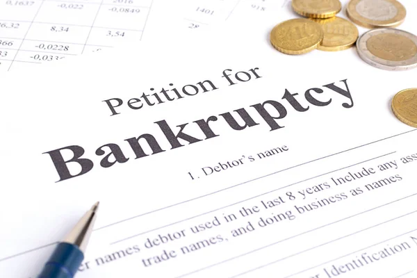 Yakın plan iflas dilekçesi, kalem ve altın sikkeler.