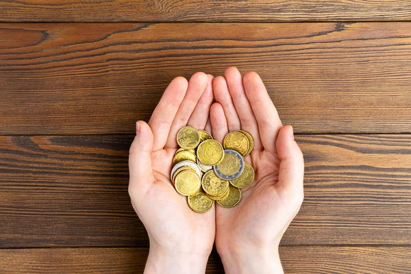 Mãos segurar pilha de moedas de euro em fundo de madeira . — Fotografia de Stock