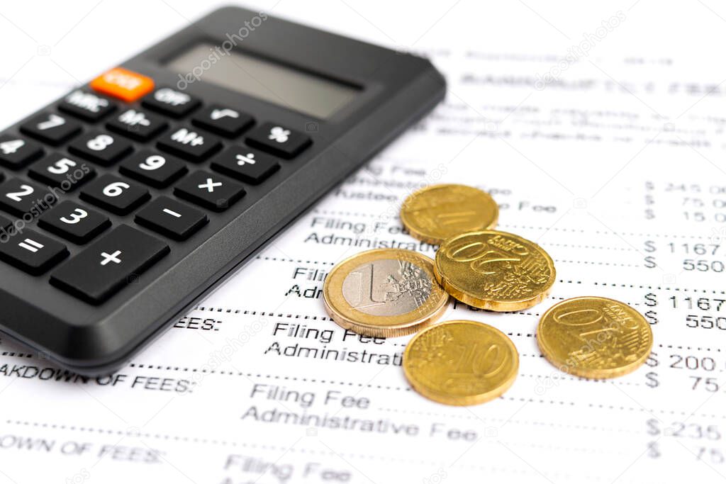 Close-up coins and calculator at bills and documents background. Finance concept.
