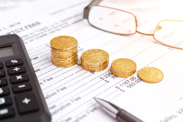 İflas kavramı. Mali raporda yakın plan madeni paralar, kalem, hesap makinesi ve gözlükler.