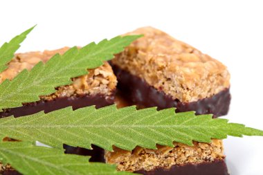 Vücudu ve zihni rahatlatmak için tıbbi kenevir CBD ilaveli şeker. Beyaz yalıtılmış arka planda yeşil marihuana yapraklarının yanında tatlı esrar şekeri CBD Cannabidiol