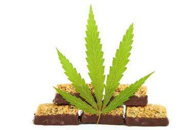 Vücudu ve zihni rahatlatmak için tıbbi kenevir CBD ilaveli şeker. Beyaz yalıtılmış arka planda yeşil marihuana yapraklarının yanında tatlı esrar şekeri CBD Cannabidiol