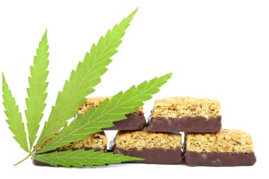 Vücudu ve zihni rahatlatmak için tıbbi kenevir CBD ilaveli şeker. Beyaz yalıtılmış arka planda yeşil marihuana yapraklarının yanında tatlı esrar şekeri CBD Cannabidiol