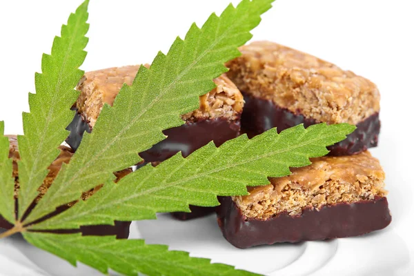 Vücudu ve zihni rahatlatmak için tıbbi kenevir CBD ilaveli şeker. Beyaz yalıtılmış arka planda yeşil marihuana yapraklarının yanında tatlı esrar şekeri CBD Cannabidiol