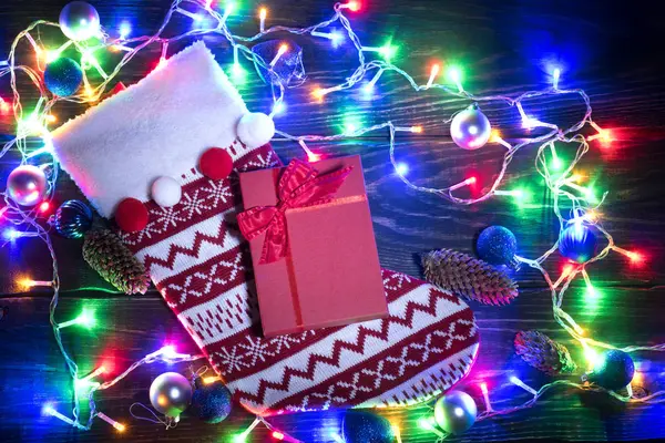 Χριστουγεννιάτικη κόκκινη κάλτσα και λαμπερά γιρλάντα — Φωτογραφία Αρχείου