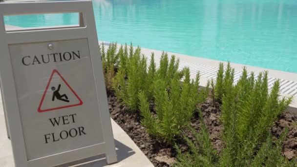 Señal de precaución suelo mojado en la piscina al aire libre . — Vídeos de Stock