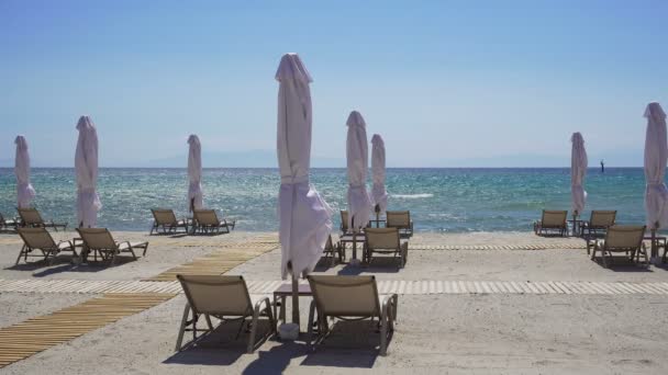 Lettini con ombrelloni chiusi su una spiaggia con sabbia . — Video Stock