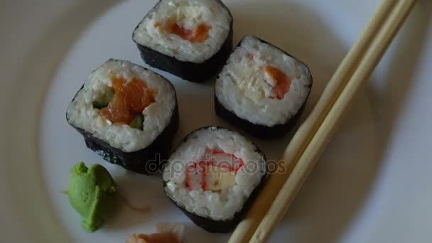 Japanese sushi rolls variety close up rotating on a white dish. — Stock Video