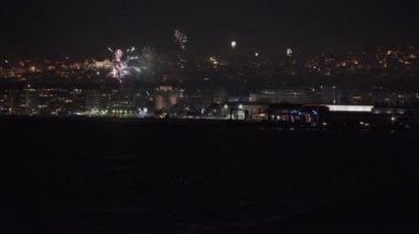 Geceleri geniş yerleşim alanlarının üzerinde havai fişek gösterisi. Yeni Yıl Arifesi 01 Ocak 2020 'de Yunanistan' ın Selanik kentinde yeni yılın gelişi için havai fişekler kentin limanından görüldü..