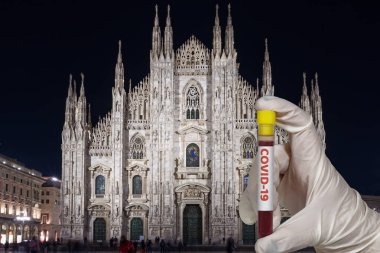 Milan, İtalya Coronavirus COVID-19 dünya salgını konsepti. Eldivenli kimyager 2019-nCoV karantinasını göstermek için gece Duomo Milano Katedrali 'nden önce 2019-nCoV virüsü taşıyan boş bir kan tüpü tutuyor.