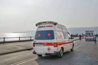 Naples, Italy - February 21 2019: Italian Red Cross Ambulance speeding on street during medical emergency. Croce Rossa Italiana cars running through the streets of Naples waterfront, at Via Partenope. clipart