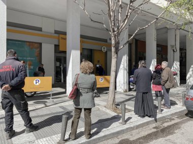 Selanik, Yunanistan - 16 Mart 2020: Coronavirüs tedbirleri iş ve günlük yaşamı etkiliyor. Yunan halkı, Yunan hükümetinin COVID-19 'un yayılmasını önleme kararı doğrultusunda bankanın dışındaki mesafesini koruyor.