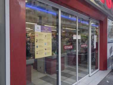 Selanik, Yunanistan - 20 Mart 2020: Coronavirus güvenlik işaretli Super Market girişi. Yunanistan Sağlık Bakanlığı tarafından COVID-19 tedbirleriyle yayınlanan pencere levhası çıkartması.