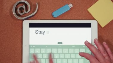 Gezici bilgisayarla çekilmiş ev virüsü karantina konseptinden çalışmalar. Kadın daktilo POV bir tablet üzerinde ev mesajı kalır, bir USB çubuk ve sarı notlar etrafında kağıtlar.