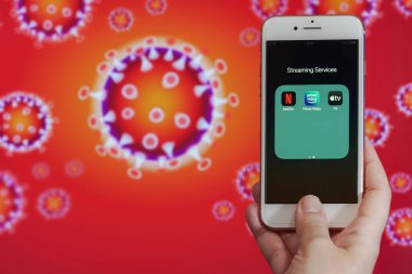 Selanik, Yunanistan - 21 Mart 2020: Akış Hizmetleri Coronavirus kavramı bit oranı sınırlaması. Netflix, Amazon Prime Video & Apple TV artı logolarla COVID-19 virüs görüntülü cep telefonundan önce el ele tutuşur.