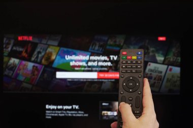 Selanik, Yunanistan - 21 Mart 2020: Netflix Streaming Service VoD içerik sağlayıcısı kavramı. Netflix uygulaması çevrimiçi saat giriş sayfası olan bir ekrandan önce el bir çokluortam uzaktan kumandası tutar.