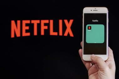 Selanik, Yunanistan - 21 Mart 2020: Netflix Streaming Service VoD içerik sağlayıcısı kavramı. Ekrandan önce Netflix çevrimiçi saat uygulama logosuna sahip bir cep telefonu tutun.