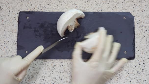 衛生上の予防手袋でまな板の上に生のポルトベッロキノコをカット 調理後の女性のトップビュー健康細菌予防措置 ナイフ白キノコで切断 — ストック動画