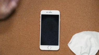Yaygın enfeksiyon riskini azaltmak için etkili bir derin temizlik cep telefonu. Kadın dezenfektan kullanmak için güvenli spreyler ve temizlemek için mikrofiber bez ile akıllı telefon ekranını ovuyor..