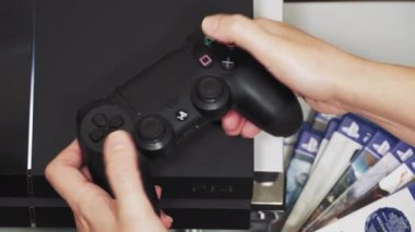 Selanik, Yunanistan - 10 Nisan 2020: PlayStation 4 DualShock 4 kablosuz kontrolörüyle oynanıyor. Dişi tutucu oyun sahası PS4 oyunu oynamayı öğreniyor, onu logolu Sony oyun konsolunun üstünde tutuyor..