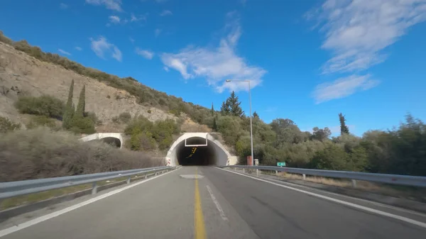 Greek empty highway tunnel entrance without traffic. Day POV view of car speeding on multi lane road at Egnatia Motorway Greece, against blue sky with clouds.