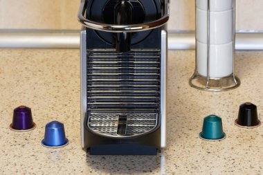 Alüminyum kapsüller kullanarak otomatik bir makinede espresso oluştur. Kahve makinesinin etrafında metal renkli kapsüller olan mutfak tezgahı. Bol kremalı sıcak damlayan kahve yapımında kullanılır..