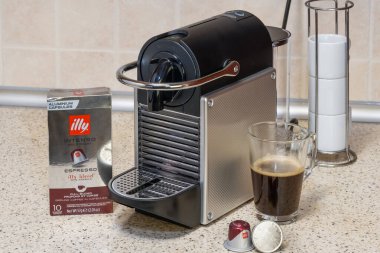 Alüminyum kapsüllerle espresso yapmak için kullanılan otomatik Nespresso makinesi. Kahve makinesinin etrafındaki metal kapsüller, kremalı sıcak kahve yapmak için..