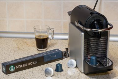 Alüminyum kapsüllerle espresso yapmak için kullanılan otomatik Nespresso makinesi. Kahve makinesinin etrafındaki Starbucks metal kapsülleri kremalı sıcak kahve yapmak için.