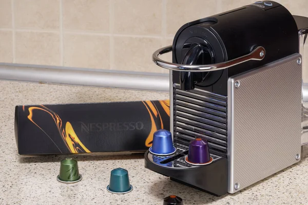 Alüminyum kapsüllerle espresso yapmak için kullanılan otomatik Nespresso makinesi. Kahve makinesinin etrafındaki metal renkli kapsüller, kremalı sıcak damlayan kahve yapmak için..