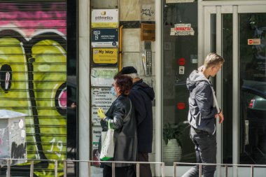 Selanik ve Yunanistan Coronavirüs tedbirleri iş ve günlük yaşamı etkiler. Maskeli ve eldivenli Yunanlılar, hükümetin COVID-19 'u önleme kararı doğrultusunda dükkanların önünde yürüyorlar.