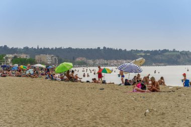 Yunanistan 'ın Neoi Epivates plajları yaz sezonu için açık. Selanik 'in varoşlarında deniz kenarında güneşli şemsiyelerle yıkanan, hükümet insanların uzak durmasını önerdikten sonra..