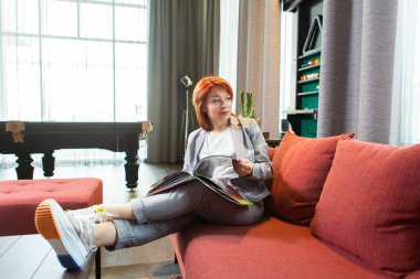 İş elbisesi giymiş bir kadın, uzak bir işte bir evin içinde boş beyaz kapaklı bir kitap ya da tablet tutuyor. Bir iş kadını için evde çalışıyorum.